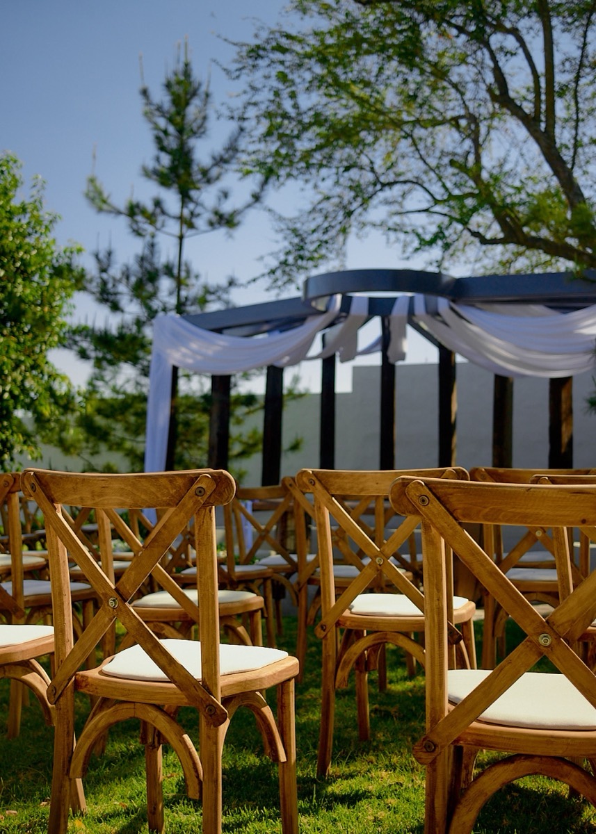 Sillas de madera frente a la pérgola de ceremonia